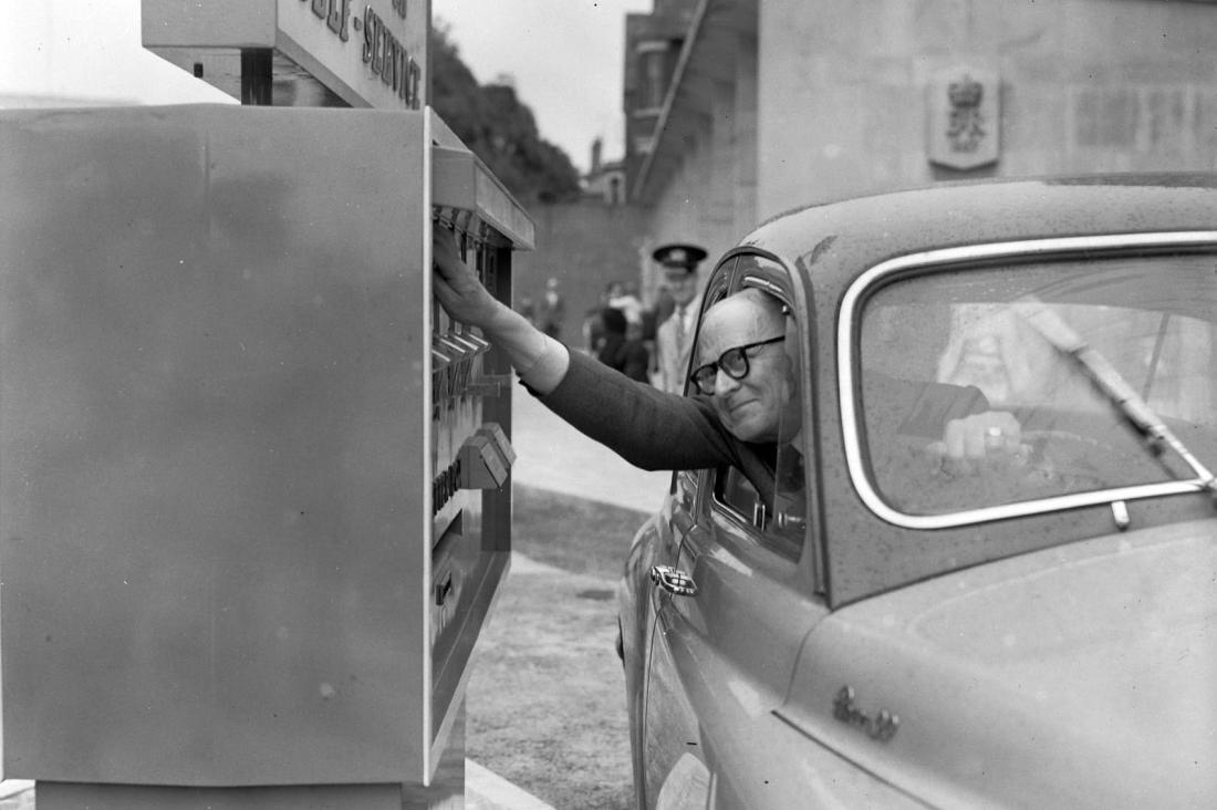 Black and white ohoto of a man posting a letter from his car window . Image Courtesy The Culture Trust / The Luton News