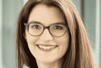 brunette woman wearing glasses smiling at the the camera
