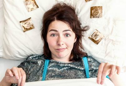 An image of Fran laying in bed surrounded by condoms