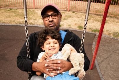 Father on Swing with child on lap - Promotional image for Fatherhood -  Image credit Graeme Braidwood